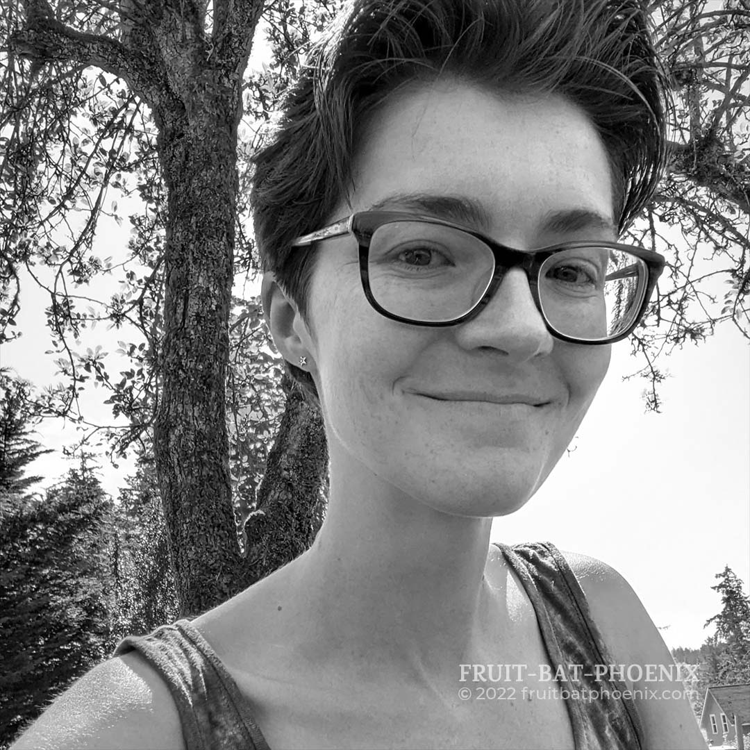 black and white of Calyn smiling with a tree in the background