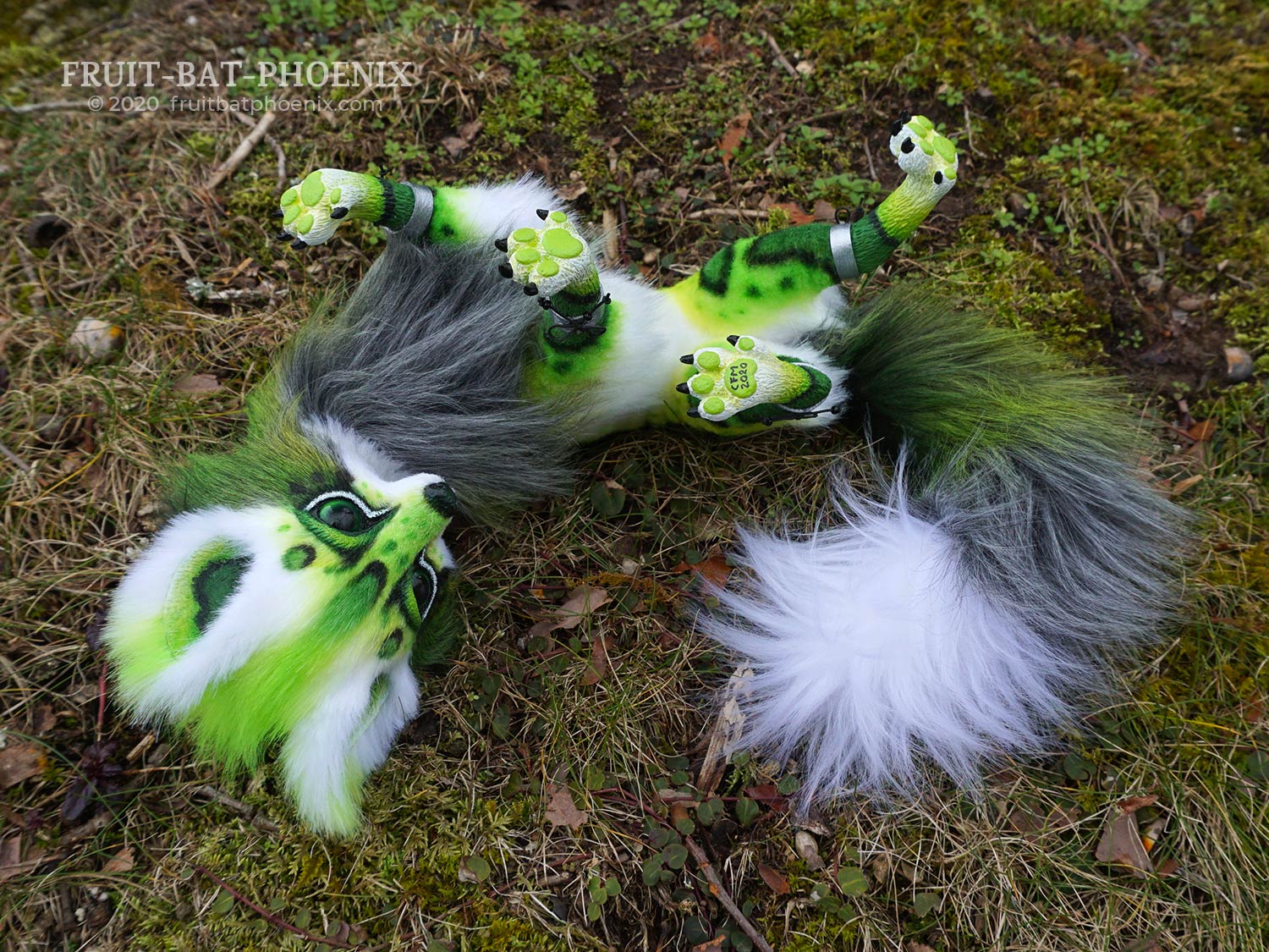 Green spotted fox posable art doll rolls on its back showing its feet.
