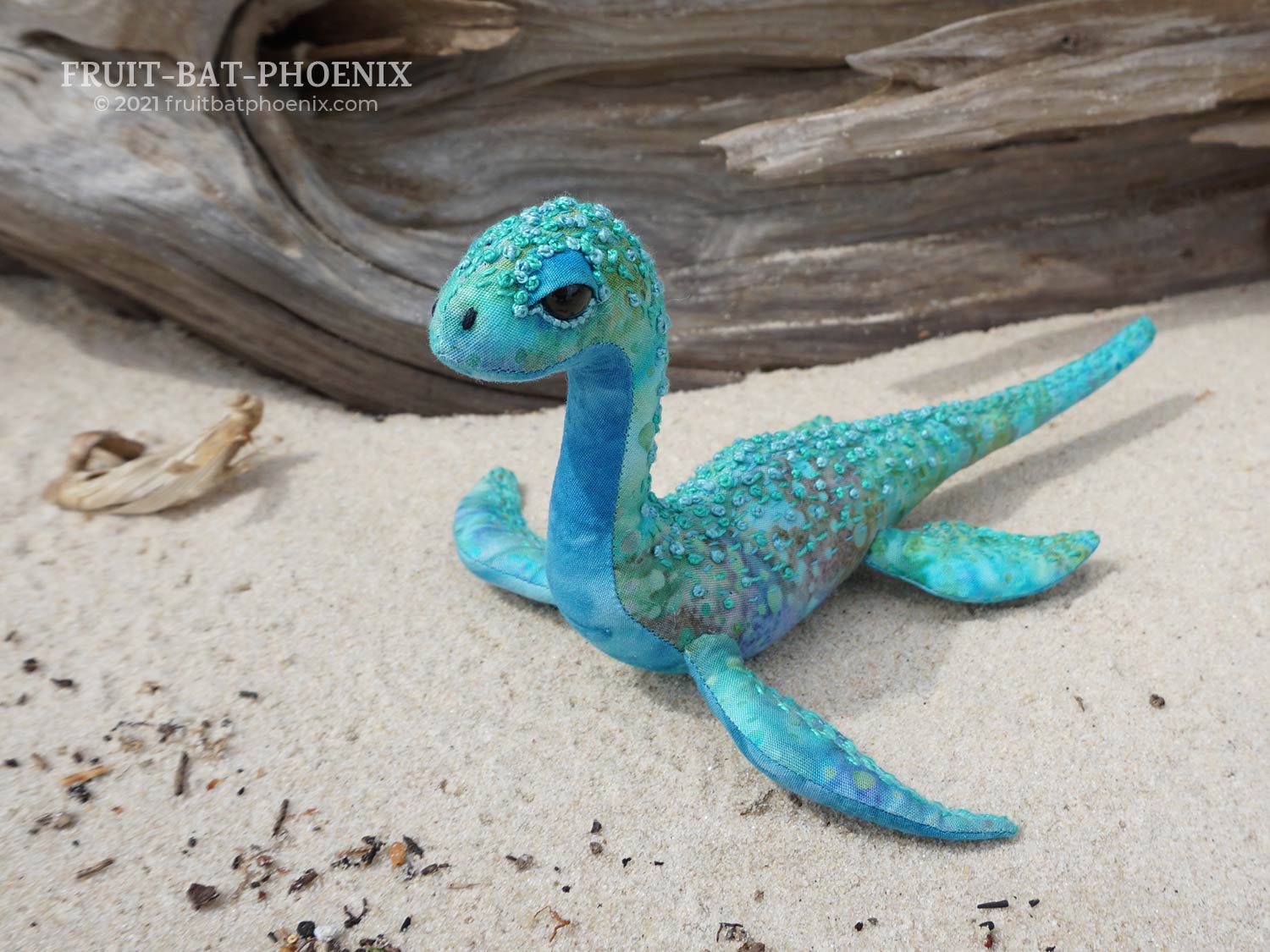 aqua nessilet plush in front of driftwood