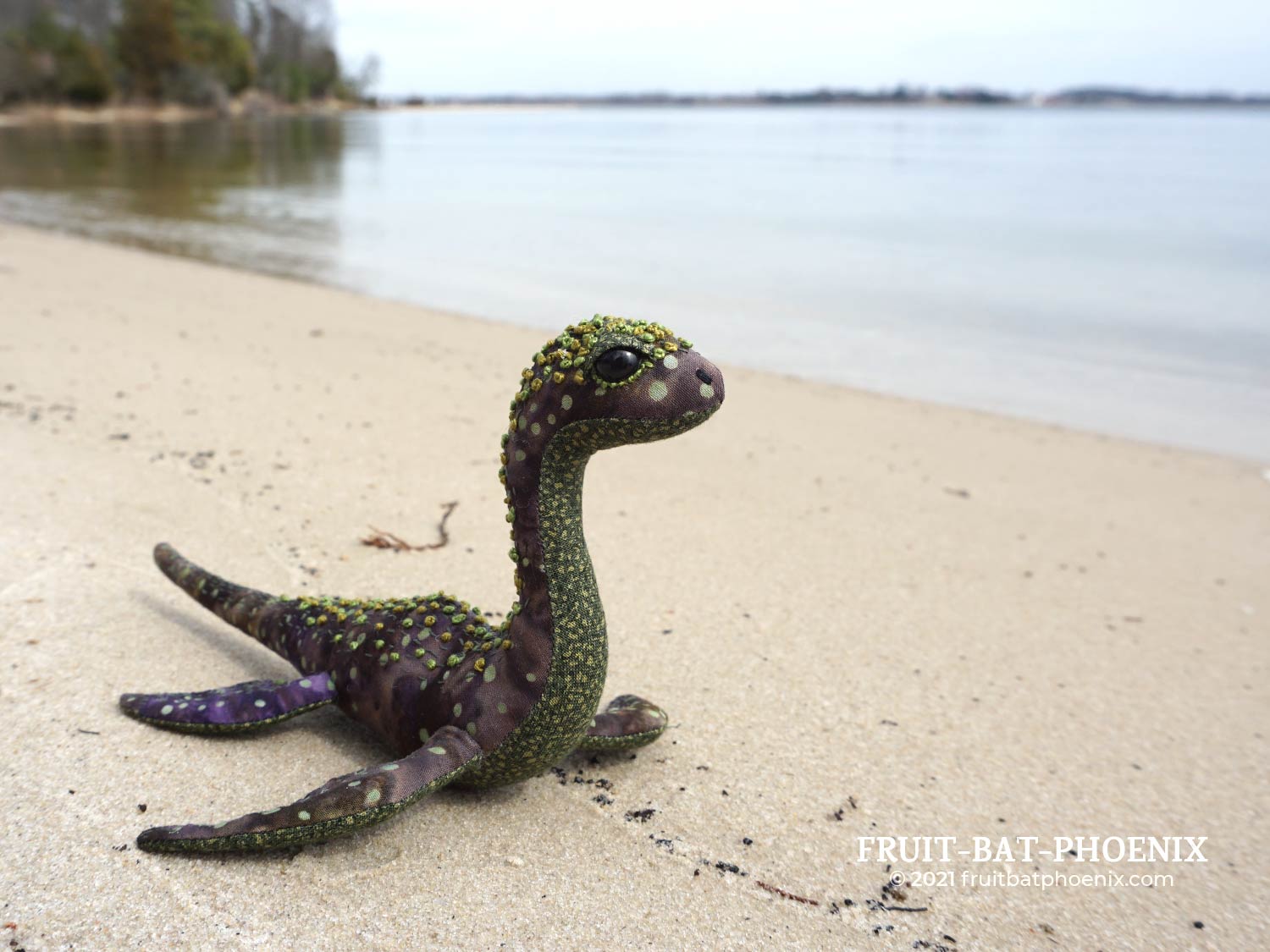 purple-green nessilet plush on a beach